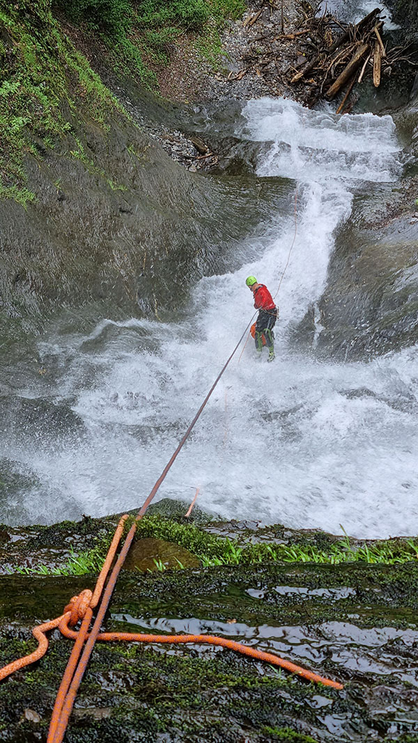 Image © Matthias Holzinger/CE4Y a person rappeling down a waterfall using red suit and jacket