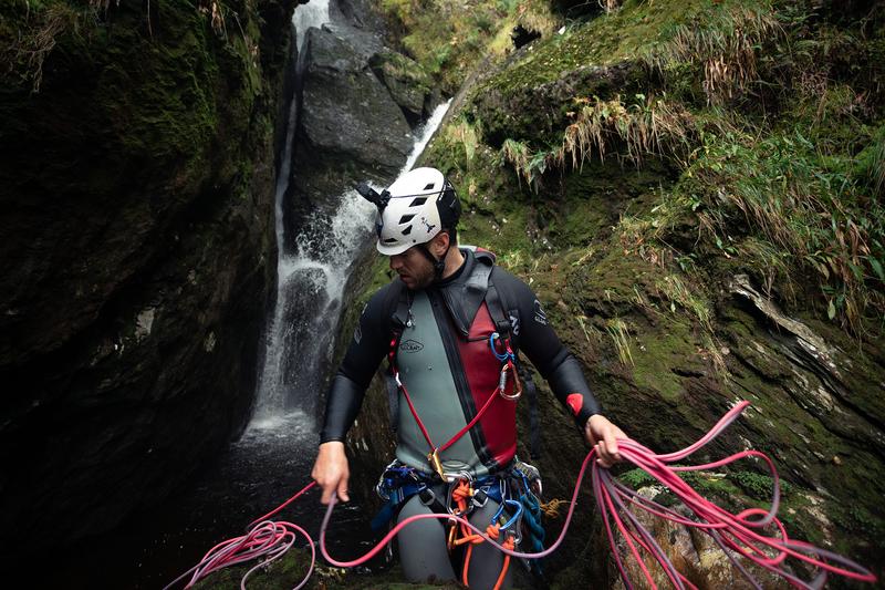 an image of a canyoneer coiling a pink rope