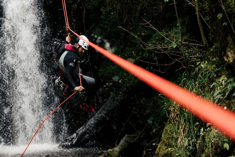 A canyoneer using a guided rappel technique.